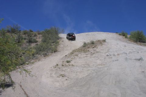 1994 Ford Bronco - A 1994 Ford Bronco navigates a challenging dirt incline under a clear blue sky.
