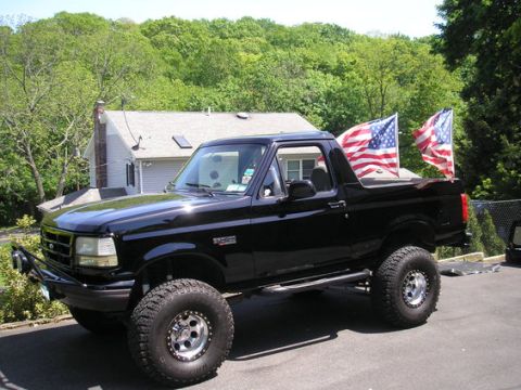 1993 Ford Bronco - This black Ford Bronco, likely a 1992 model, is equipped with large off-road tires and American flags.