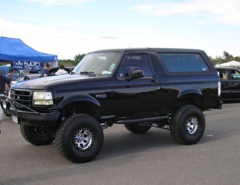 1993 Ford Bronco - This lifted black 1993 Ford Bronco features an aftermarket front bumper and large off-road tires.