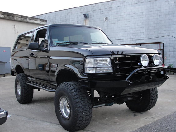 Lifted black two-door Ford Bronco with tube winch bumper and round driving lights