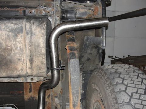 1993 Ford Bronco - A new exhaust pipe is being fitted to the underside of a vehicle, with a tire and suspension visible.