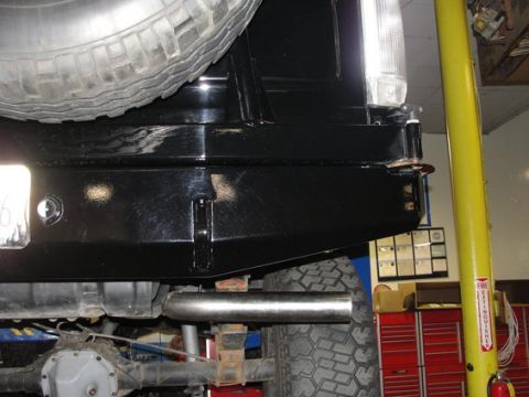 1993 Ford Bronco - The rear bumper and spare tire of a black SUV are visible, with the exhaust pipe and differential also in view.
