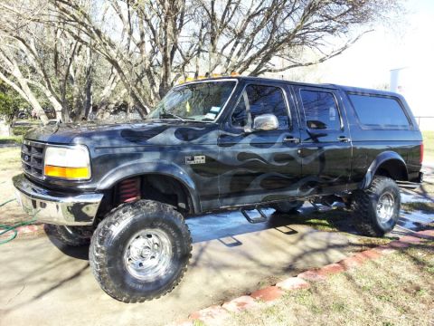 1993 Ford Bronco - This modified Ford truck features a custom SUV conversion with flame decals and significant lift.