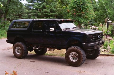 1993 Ford Bronco - This modified Ford Bronco features a lifted suspension and custom flame graphics, with a prominent aftermarket grille.