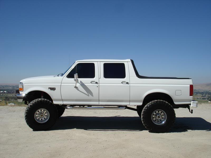 White crew cab pickup truck with large tires and lifted suspension