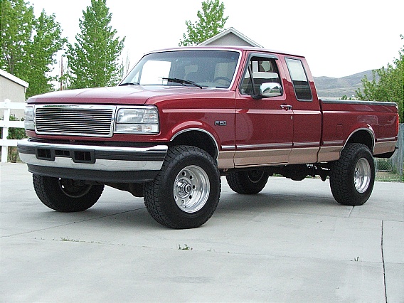 Red Ford F-150 pickup truck, two-tone tan lower body, lifted suspension, chrome grille, chrome bumper, aftermarket wheels