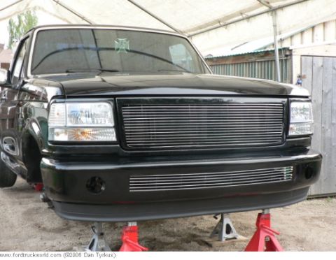 1993 Ford Bronco - This black Ford truck, likely a 1992 model based on its grille, is elevated on jack stands for maintenance.