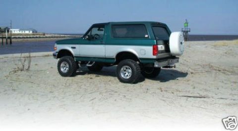 1993 Ford Bronco - This two-tone green and silver 1993 Ford Bronco is ready for adventure, parked on a sandy beach with the ocean in the background.