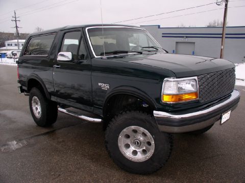 1993 Ford Bronco - A dark green 1993 Ford Bronco is shown from the front quarter angle on a cloudy day.