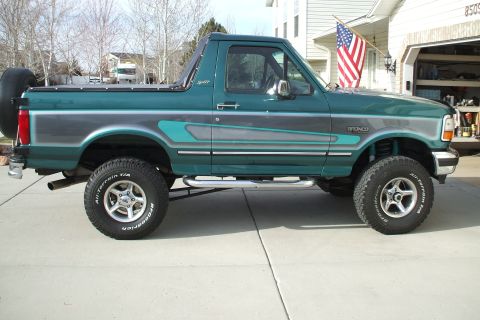 1993 Ford Bronco - This 1993 Ford Bronco is seen from the side, parked in front of a house with an American flag.