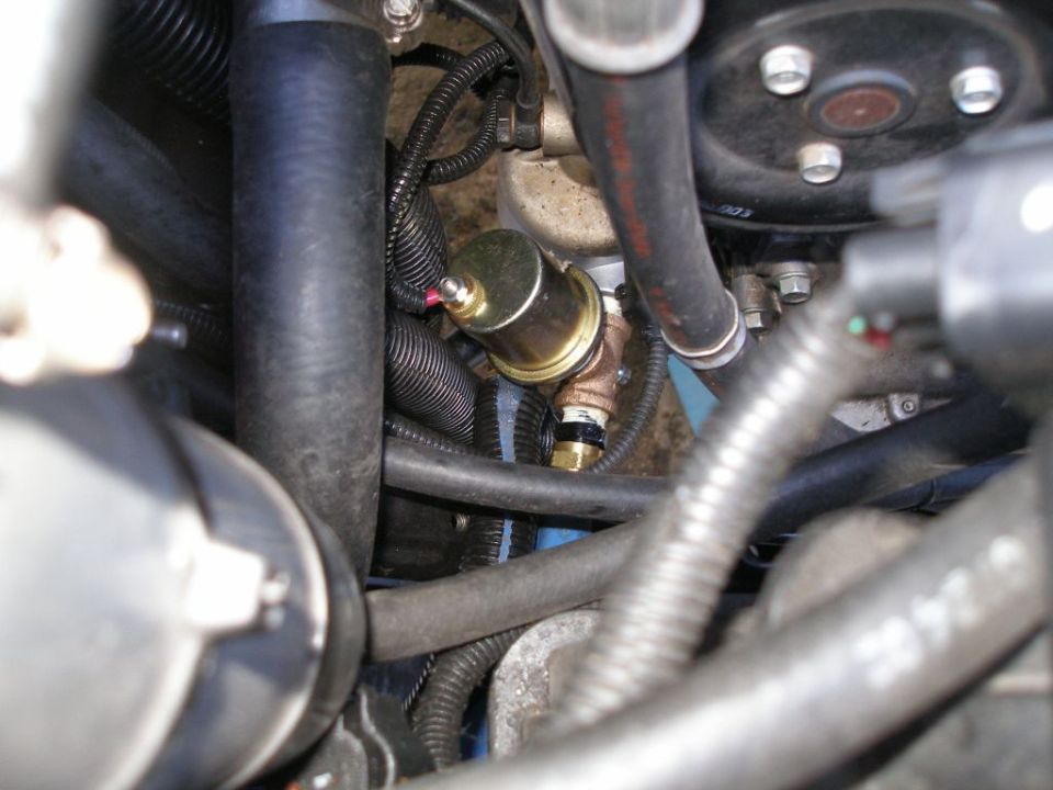 Close-up of an oil pressure sensor and associated plumbing in an engine bay