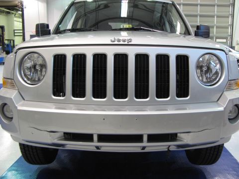 1971 Ford Ranchero - Front view of a silver Jeep Patriot with a prominent grille and a cracked bumper.