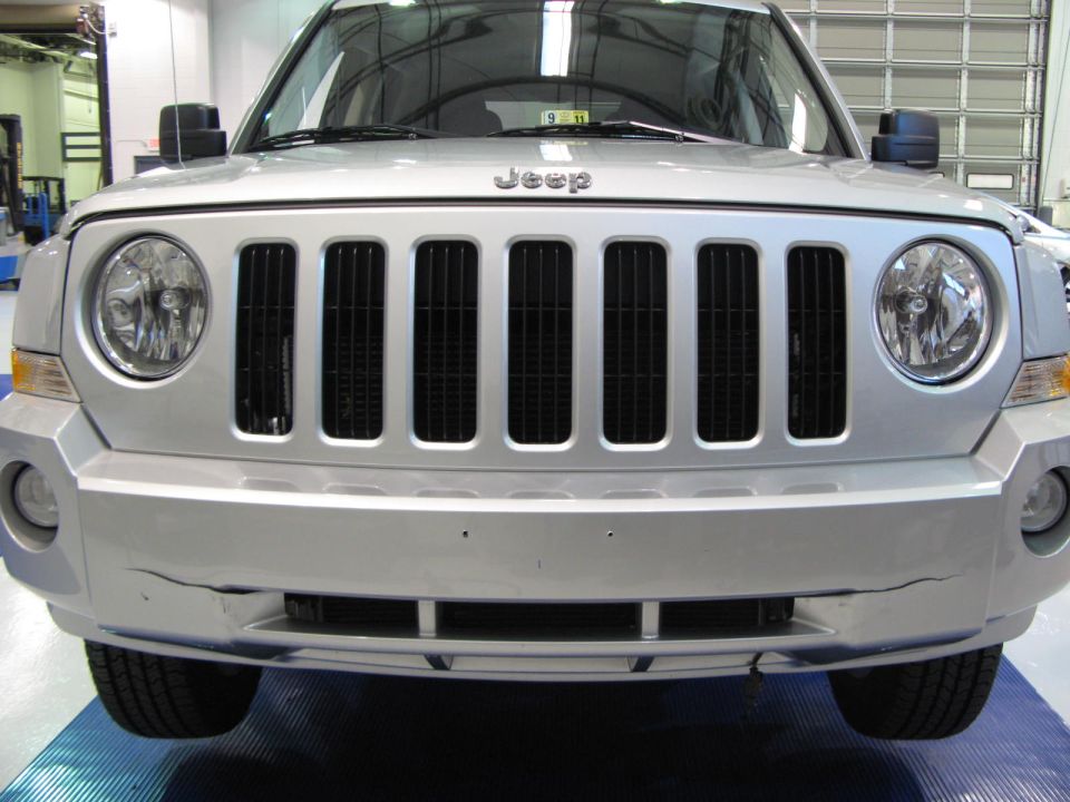Silver Jeep Patriot front view showing grille and cracked bumper