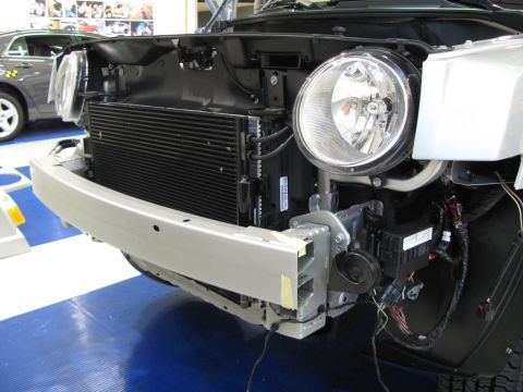1971 Ford Ranchero - The front of a vehicle is disassembled, revealing the radiator and various components. Another car is parked behind it.