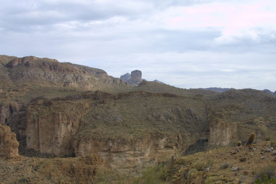 Desert mountains with a prominent rock spire in the distance and cacti in the foreground