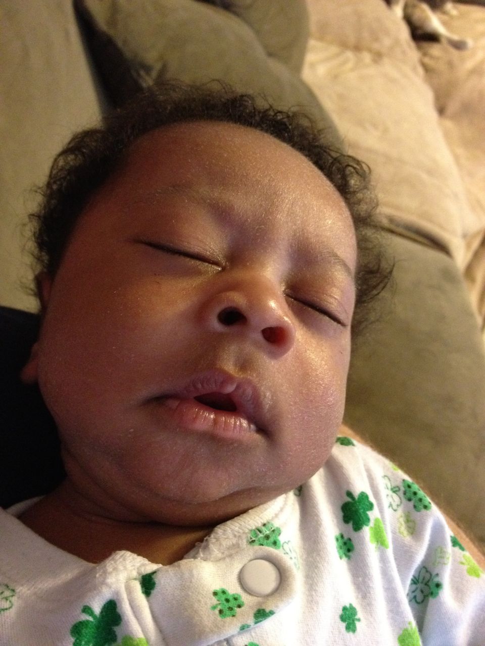 Sleeping baby in a white onesie with green shamrocks