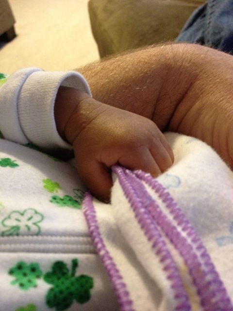 2010 Subaru Legacy - A close-up shows a baby's hand grasping a purple cord, resting on a blanket adorned with green shamrocks.