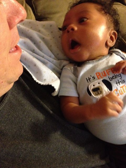 2010 Subaru Legacy - A baby yawns while looking at an adult, wearing a onesie with a dog graphic and text.
