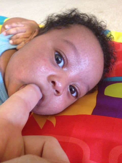 2010 Subaru Legacy - Baby sucking on thumb while lying on a colorful mat.