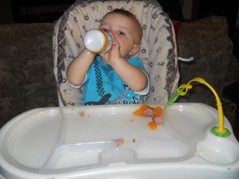 1976 Ford Bronco - A baby sits in a high chair, drinking from a bottle with food scattered on the tray.