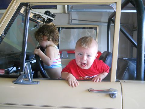 1976 Ford Bronco - Two young children are playing inside a vehicle, one pretending to drive.