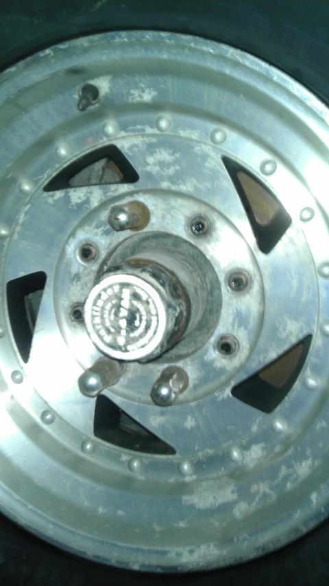 1989 Ford Bronco - A close-up view of a vehicle's wheel hub and lug nuts, showing wear and tear.