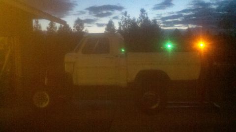 1967 Ford F-250 - A white pickup truck is parked outdoors at dusk, illuminated by green and orange lights.