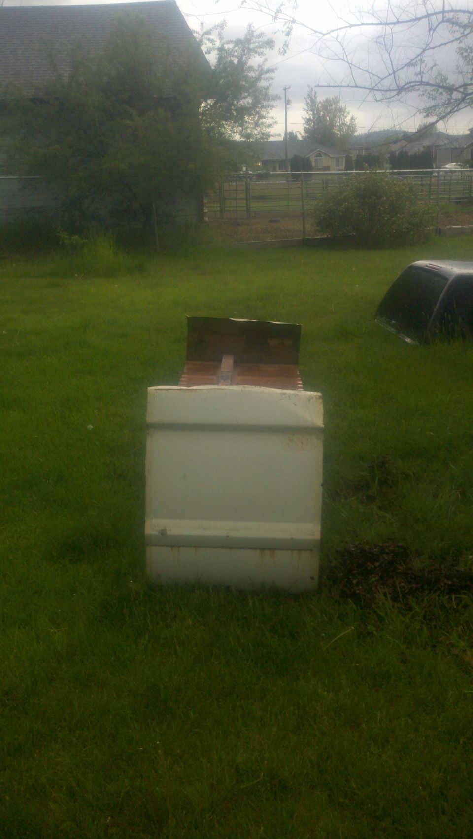 White truck bed with wooden planks on top, viewed from the rear in a grassy yard