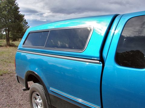 1998 Ford F-150 - A blue 1998 Ford F-150 pickup truck is shown from the side, fitted with a camper shell.