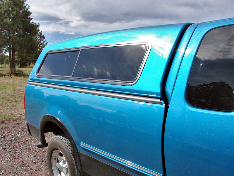 Blue 1998 Ford F-150 pickup truck side view with a camper shell
