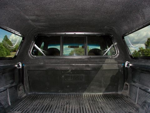 1998 Ford F-150 - Interior view of a truck bed with a fitted topper and bed liner, side windows and a rear cab window.