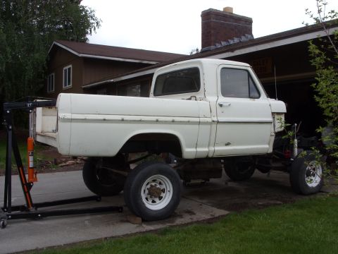 1967 Ford F-250 - White 1967 Ford F-250 pickup truck chassis is being worked on, with an engine hoist attached.