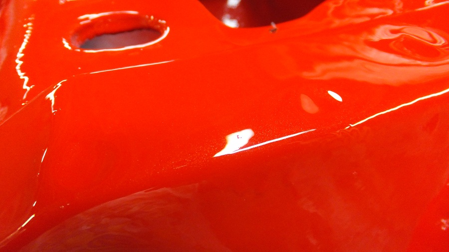 Close-up of a shiny red painted metal part with two circular indentations