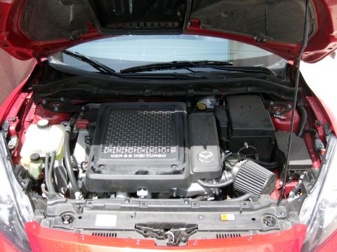 1989 Mazda MX-6 - The engine bay of a red Mazda shows the MZR 2.3 DISI TURBO engine and an aftermarket air filter.