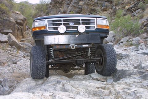 1994 Ford Bronco - Modified 1994 Ford Bronco navigating a rocky trail with its front end prominently displayed.