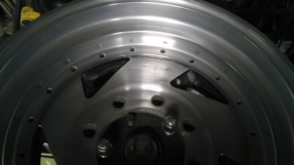 Aluminum wheel with triangular cutouts and visible lug nuts