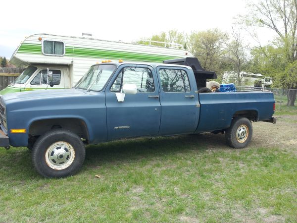Blue crew cab pickup truck parked next to an RV