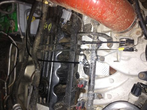 2005 Jeep Wrangler - Close-up view of engine components and throttle cables within a vehicle's engine bay.