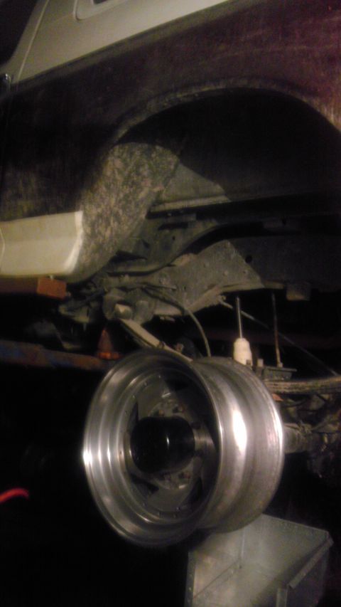 1989 Ford Bronco - Close-up view of a vehicle's rear axle and suspension, with custom wheels mounted.