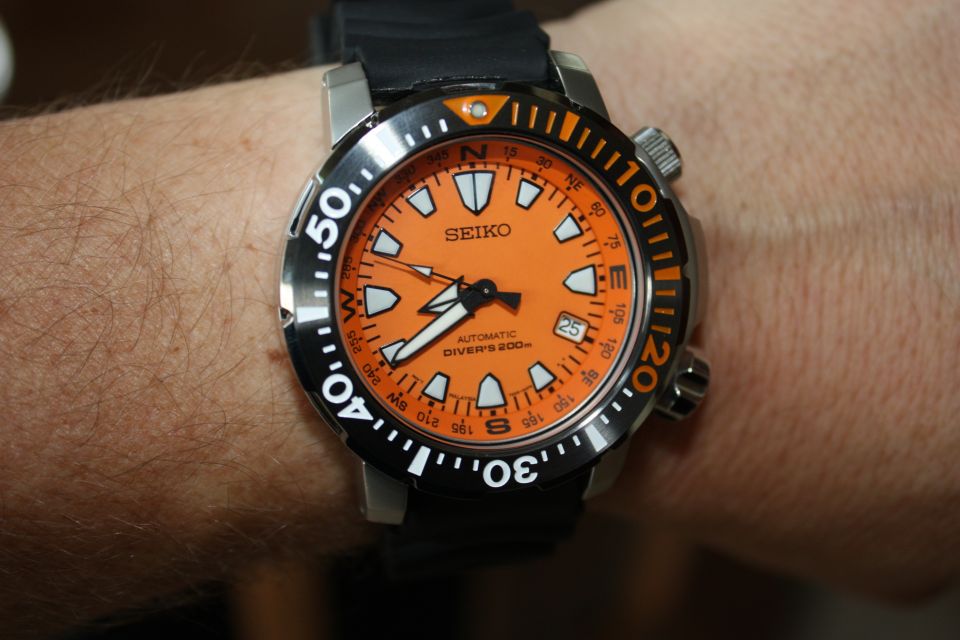 Orange dial Seiko automatic diver's watch with black strap on a person's wrist