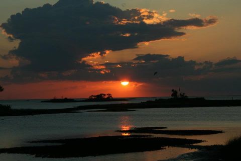 1976 Ford Ranchero - Sunset over water with silhouetted islands and dark clouds overhead.