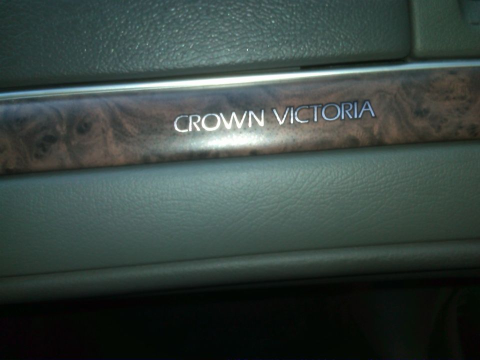 Interior trim piece with 'CROWN VICTORIA' text and wood grain accent