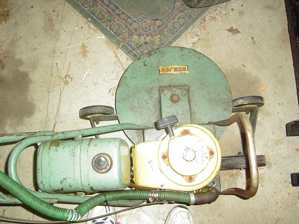 Green lawnmower with yellow engine and a label that reads "BON-MOR"