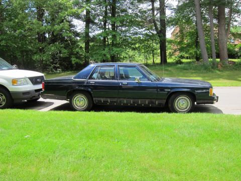 1991 Ford LTD Crown Victoria - A dark blue 1991 Ford Crown Victoria LTD is seen parked on the side of the road next to a white SUV.