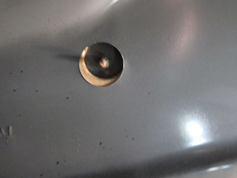 Close-up of a gray metal panel with a circular hole and visible screw head