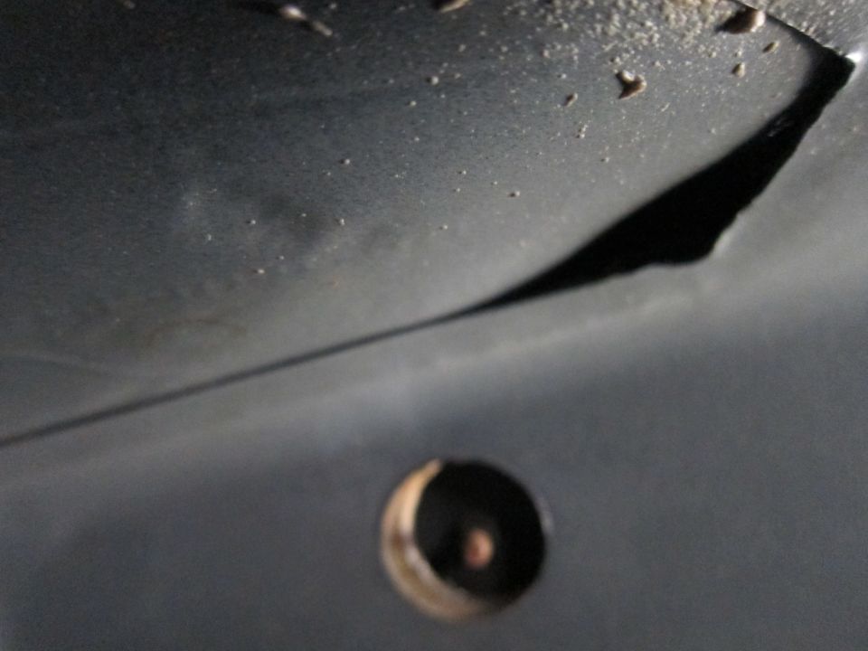 Underside of a dark vehicle with a circular hole