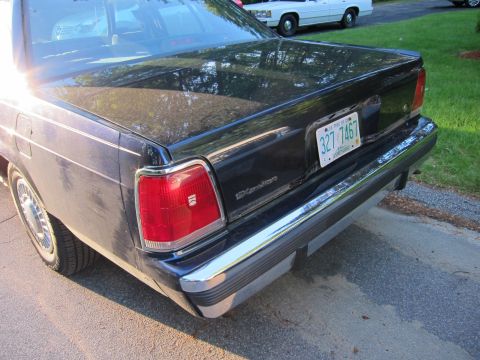 1991 Ford LTD Crown Victoria - Rear view of a 1991 Ford Crown Victoria LTD, showing its distinctive taillights and chrome bumper. Another vehicle is visible in the backgr…