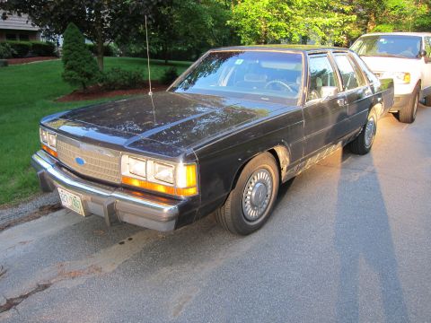 1991 Ford LTD Crown Victoria - Black Ford Crown Victoria sedan parked on a residential street with a white SUV behind it.