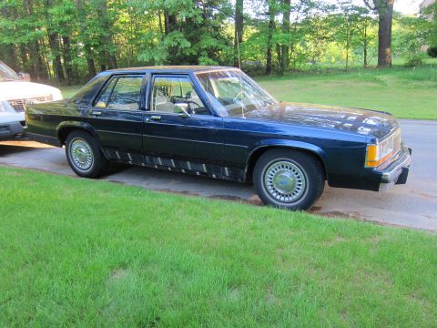 1991 Ford LTD Crown Victoria - A dark blue 1991 Ford Crown Victoria is parked on the side of the road next to a grassy area.
