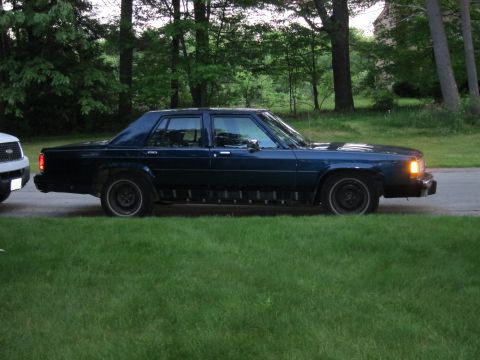 1991 Ford LTD Crown Victoria - A dark blue 1991 Ford Crown Victoria LTD is seen from the side, parked next to a white SUV.